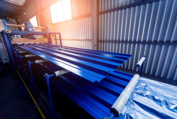Fabricated metal sheets painted blue in a warehouse setting with light shining through a window.