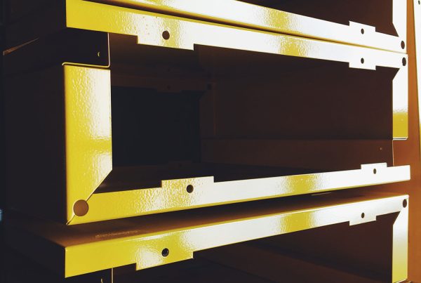 Manufactured metal pieces that have been painted bright yellow stacked neatly and waiting to be packed and shipped